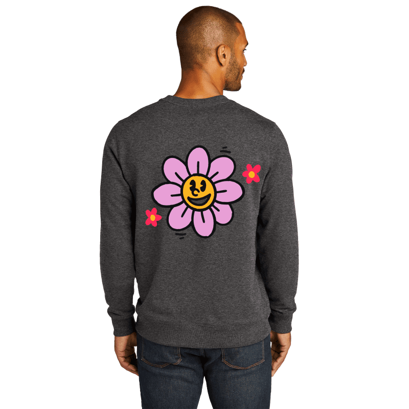 Man wearing jeans and a sweater with a big smiling flower on the back.