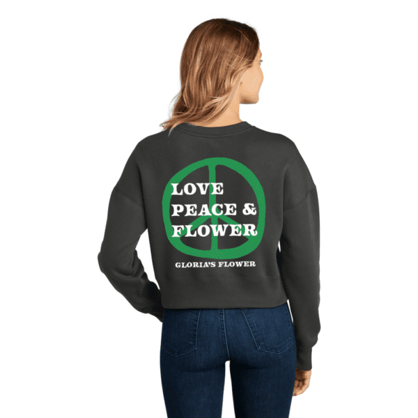 A woman wearing a sweatshirt with the words " love peace & flower ".